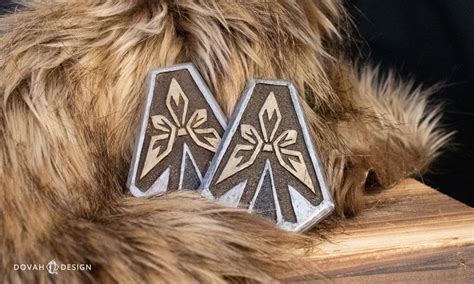 two silver and black earrings sitting on top of a wooden table next to a fur coat