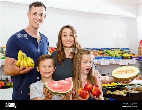 Smiling family with kids showing fresh delicious fruits during family ...