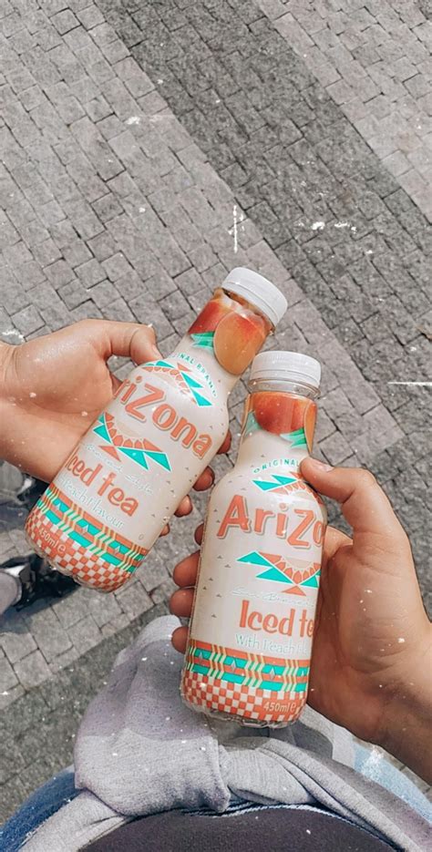 two bottles of orange juice being held by someone's hand on the street side