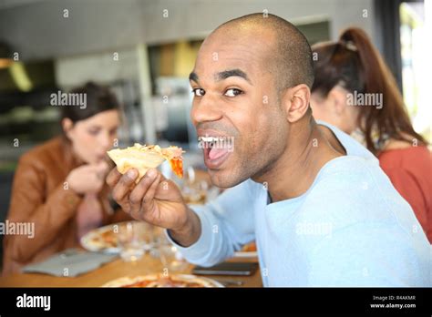 Young man having eating pizza slice Stock Photo - Alamy