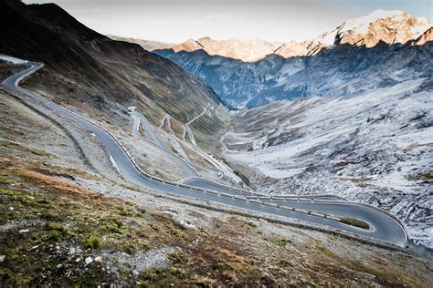 a mountain road winding down the foot of a valley, serpentine mountain ...