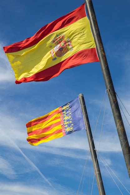 Premium Photo | Flag of spain and the flag of valencia against the blue sky