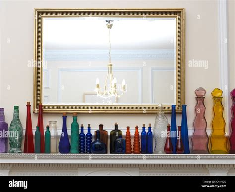 A Collection Of Glass Bottles All Different Shapes, Sizes And Colours In A Row On A Mantlepiece ...