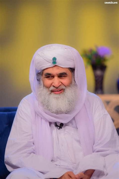 an old man with a long white beard wearing a purple turban sitting on a blue couch