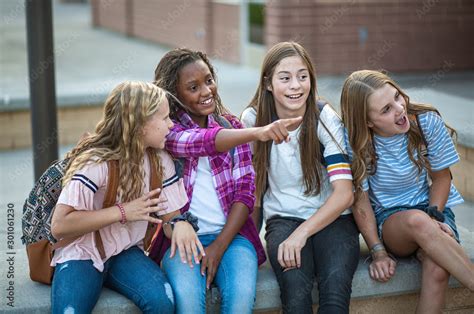 Candid photo of a group of teenage girls socializing, laughing and talking together at school. A ...