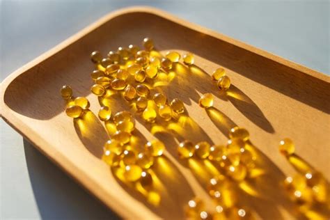 Premium Photo | Vitamin d3 gel capsules on a wooden tray solar vitamins