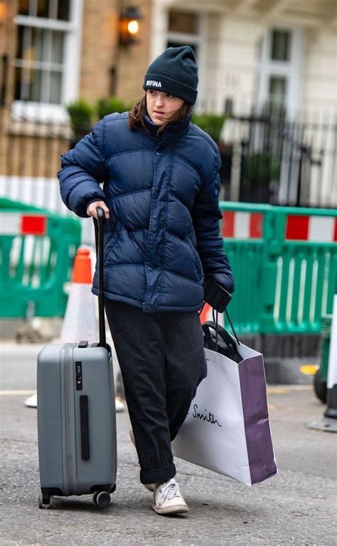 a woman walking down the street with her suitcase and shopping bags in ...