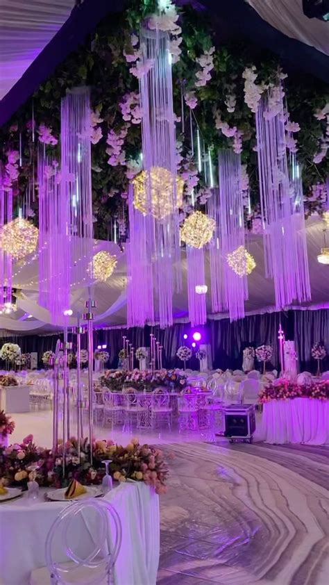 an indoor wedding venue with purple lighting and chandeliers hanging ...