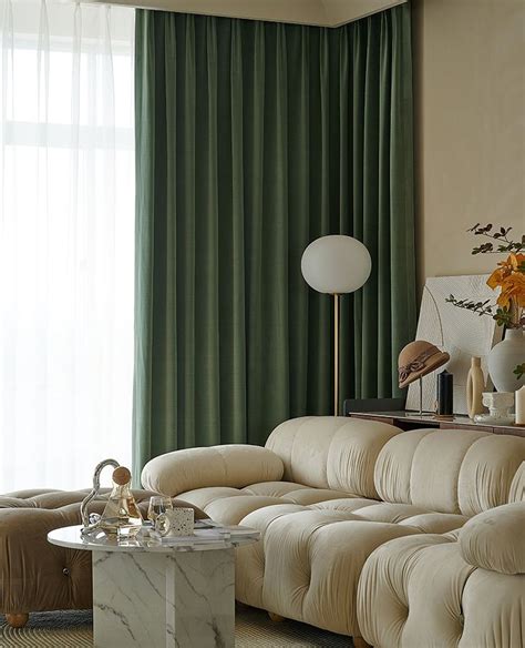 a living room filled with furniture and a large window covered in green drapes