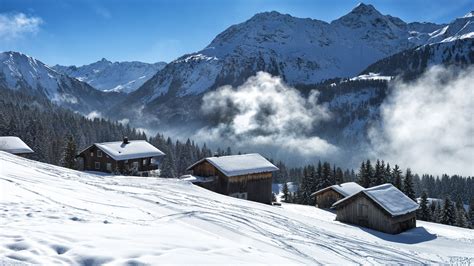 Winter landscape with ski lodges beside the ski slope and the forest, Vorarlberg, Austria ...