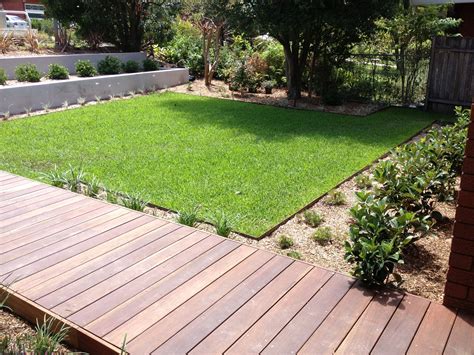 a backyard with wooden decking and green grass