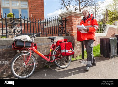 Royal Mail postman with bicycle delivering post in the village of ...