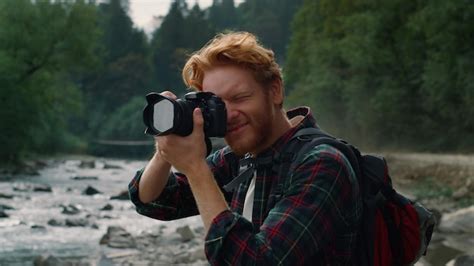 Premium Photo | A man with a camera on his head takes a photo of a river and mountains in the ...