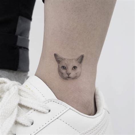 Tiny cat head tattoo on the ankle.