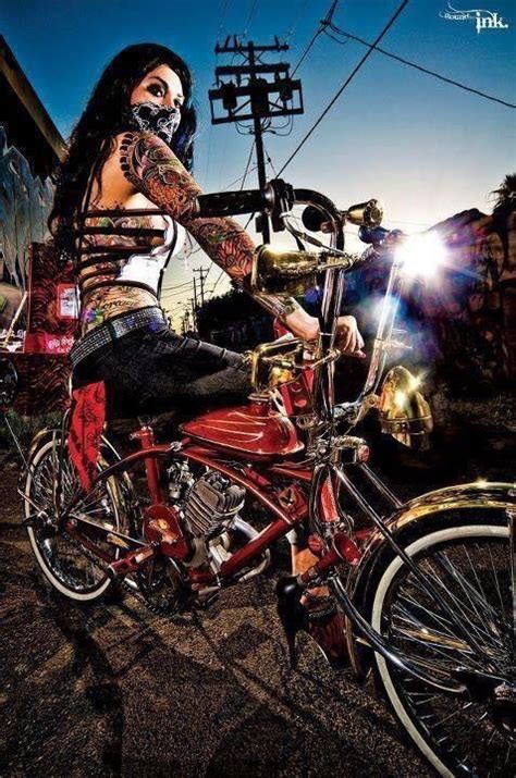 a woman sitting on top of a red motorcycle with her face painted like a skeleton