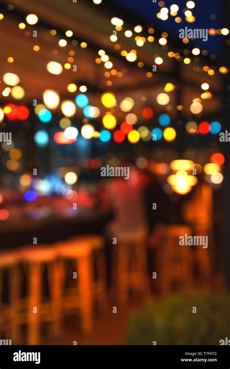 Blurred background of people sitting at restaurant, bar or night club with colorful lights bokeh ...