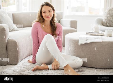 Portrait smiling barefoot woman in living room Stock Photo - Alamy