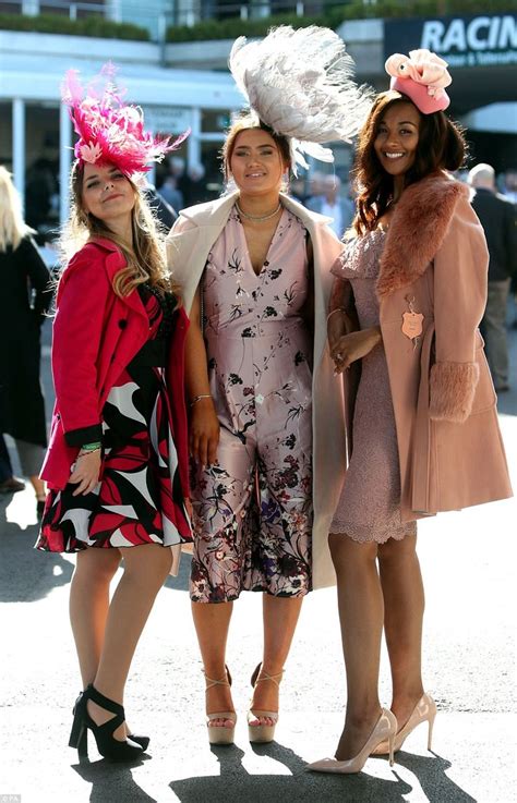 three women standing next to each other in front of a crowd wearing dresses and hats