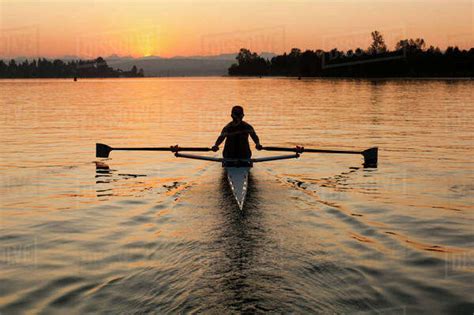 Person rowing sculling boat on river - Stock Photo - Dissolve