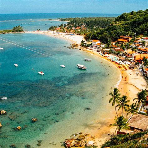 an aerial view of a beach with boats in the water and houses on the shore