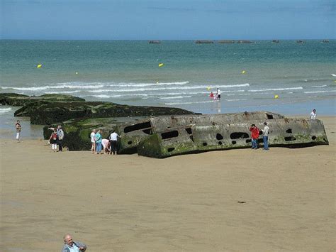 people are walking on the beach next to an old ship that has been ...