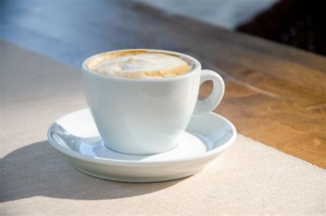 Premium AI Image | Cappuccino coffee in white cup on wood table