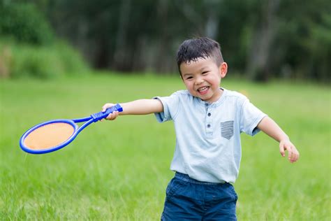 Thrilled little boy playing tennis at park - Playo