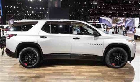 a white chevy suv is on display at an auto show, with people standing ...