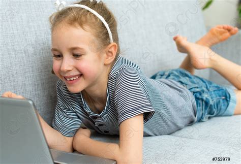 Smiling little girl on the sofa with laptop - stock photo 753979 | Crushpixel