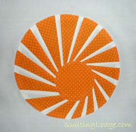 an orange and white circular design on a piece of fabric with the sun in the center