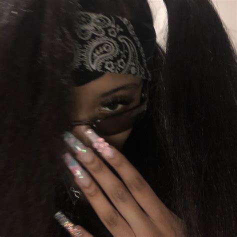 a close up of a person with long hair wearing a mask and holding her hands to her face