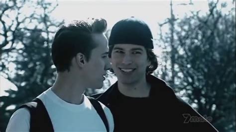 two young men standing next to each other in front of some trees and ...