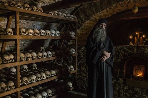 Greek Orthodox monk in front of the skulls of monks that lived in his ...