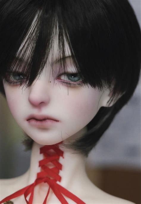 a close up of a doll with black hair and red ribbon around it's neck