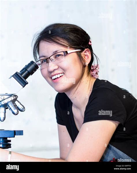 Woman sitting in research laboratory looking through microscope Stock Photo - Alamy