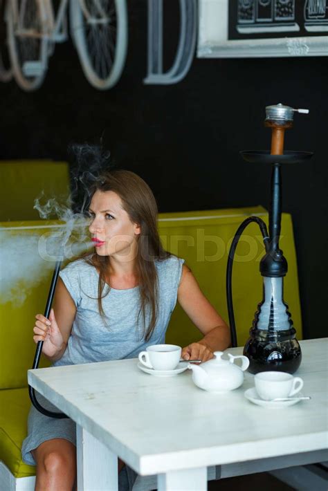 Beautiful woman smoking a hookah and drinking tea in a cafe | Stock image | Colourbox