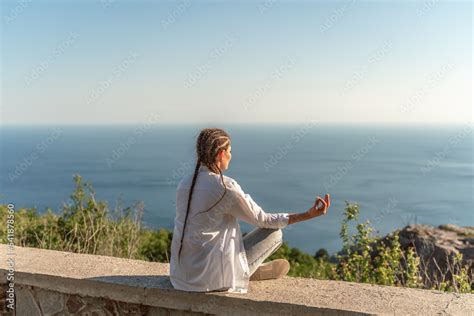 Profile of a woman doing yoga in the top of a cliff in the mountain ...