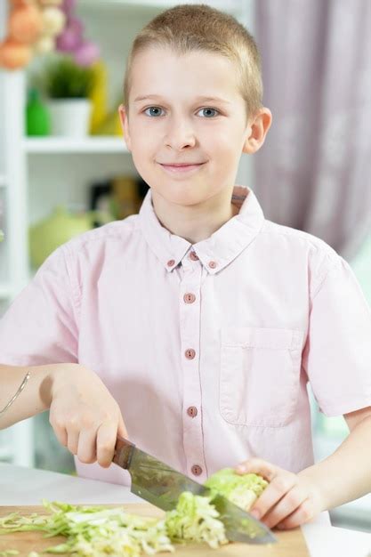 Premium Photo | Cute boy preparing salad on kitchen table at home