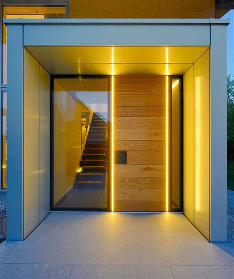 the entrance to a modern house is lit up with yellow lights and ...