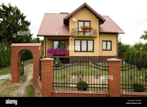 Modern Polish house with wrought iron fence with brick pillars and Stock Photo: 68938595 - Alamy