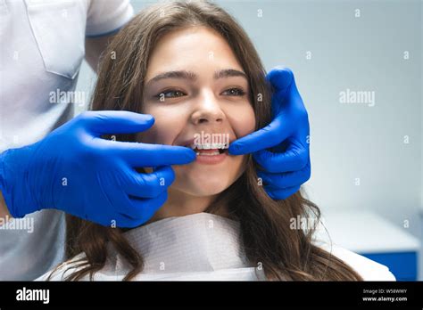 beautiful young brunette woman having examination at dental office while dentist showing ...