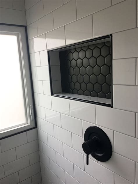 Shower niche with 2" black matte hex tile accent, white 4" x 8" subway tiles and Schluter bl ...