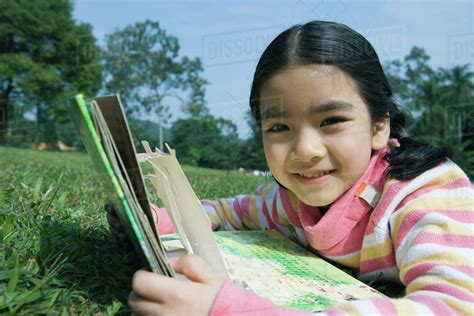 Girl lying in grass with pop-up book - Stock Photo - Dissolve