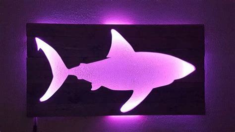 a purple light that is on the side of a wall with a shark in it