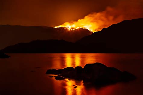 Forest fire at night reflecting in nearby lake. - Drax