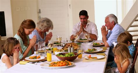 Extended Family Praying Together Before Dinner At Home In The Dining ...