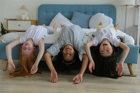 Happy multiethnic little girls lying on bed · Free Stock Photo