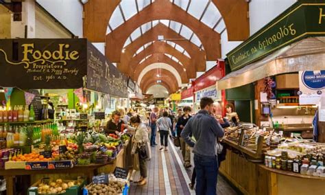 people are shopping in an indoor market with lots of fresh fruits and vegetables on display