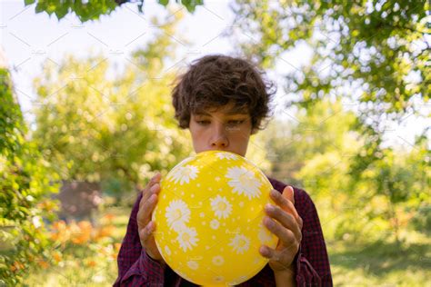 young boy blowing into the balloon o | Stock Photos ~ Creative Market