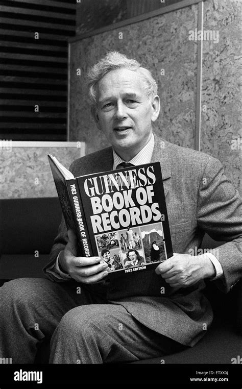 Norris McWhirter holding a copy of the Guinness Book of records, which he co-founded with his ...